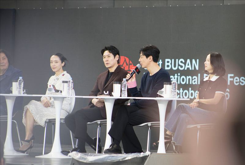 영화제 무대 위 흰 테이블에 앉아 마이크를 들고 이야기를 나누는 게스트들